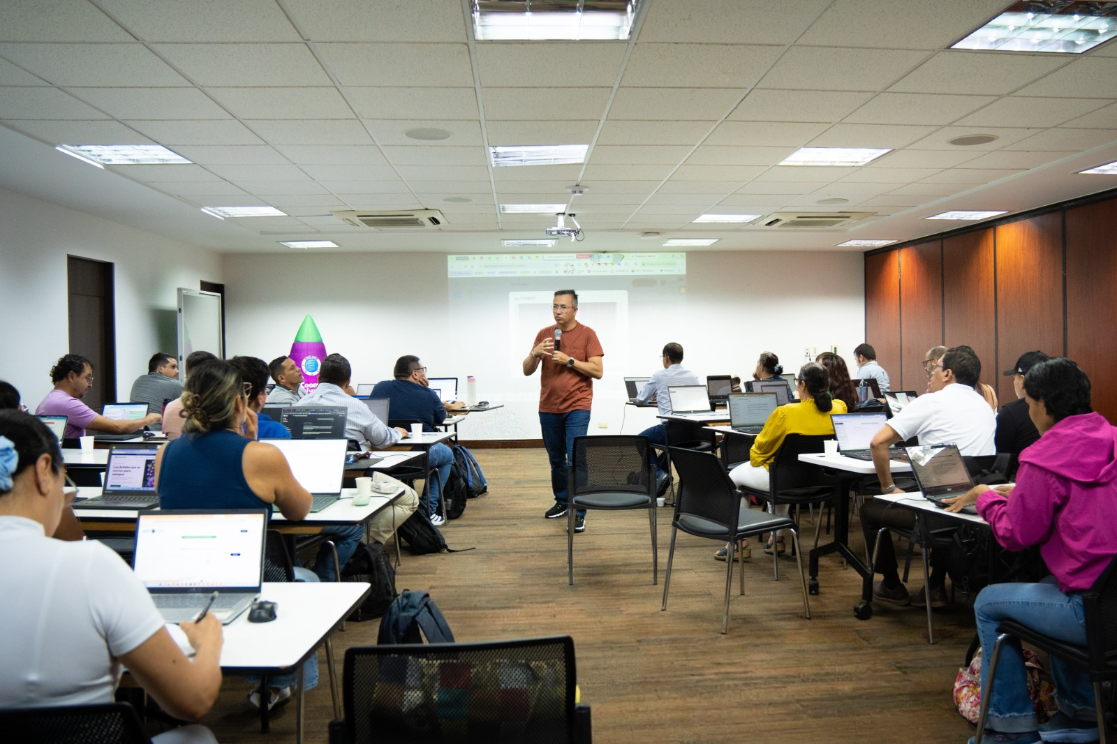 Salón lleno de docentes trabajando con portátiles